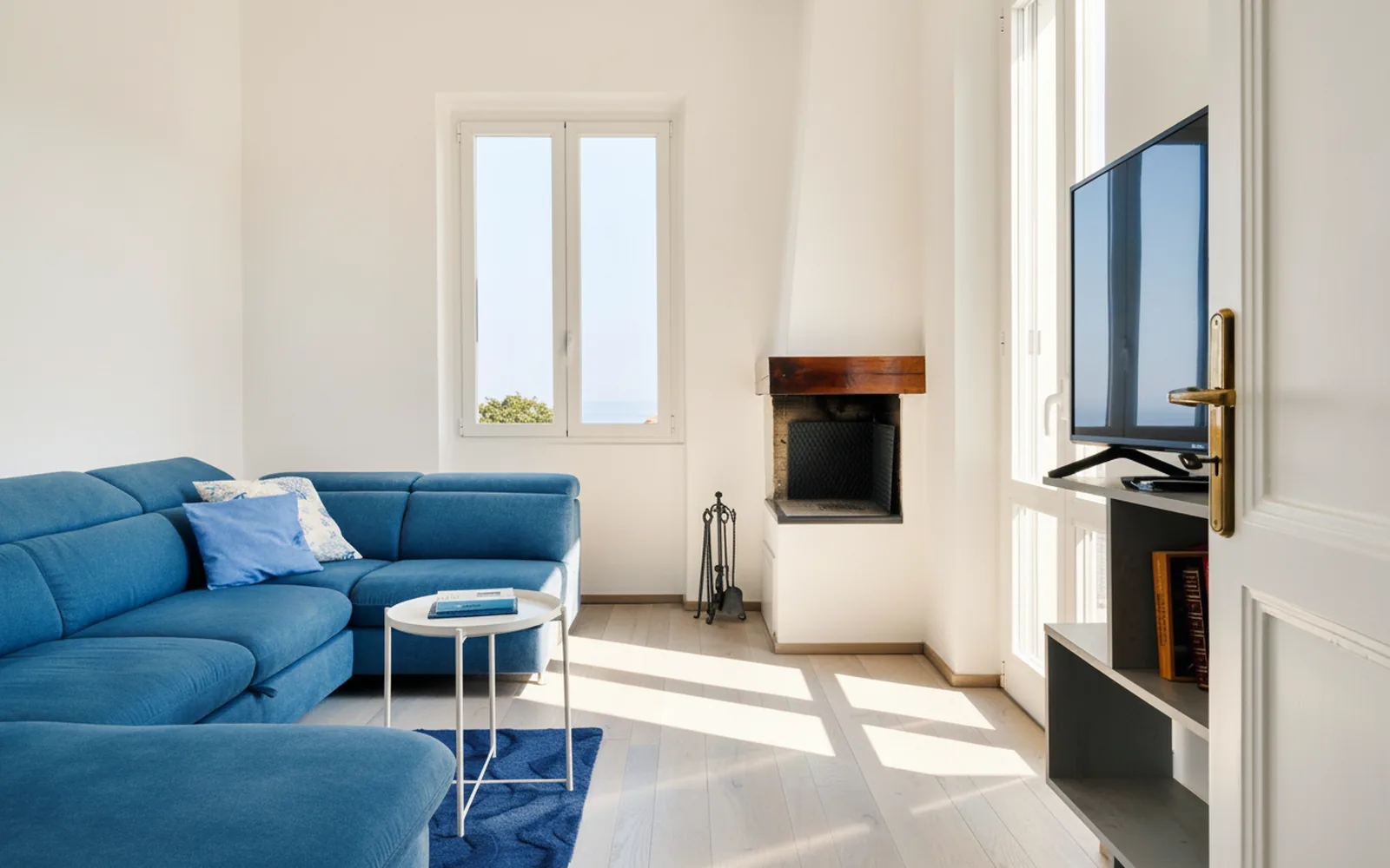 Il soggiorno con divano angolare blu e TV